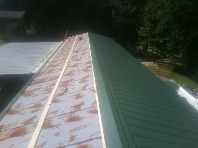 Old rusted panels beside newly installed green metal roofing — Wind Damage Roof Repair by Roofing Brothers in Triadelphia