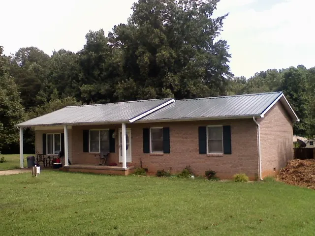 Gray metal roof on a brick ranch house with a side carport in Triadelphia