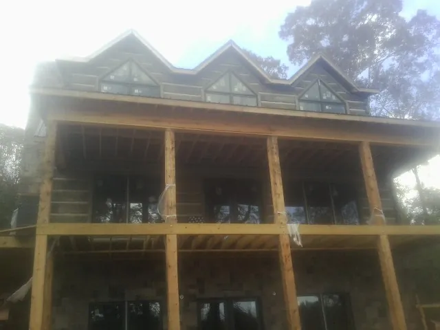 Dormers and porch framing on a large log home under construction — Roof Coating work by our crew in Triadelphia