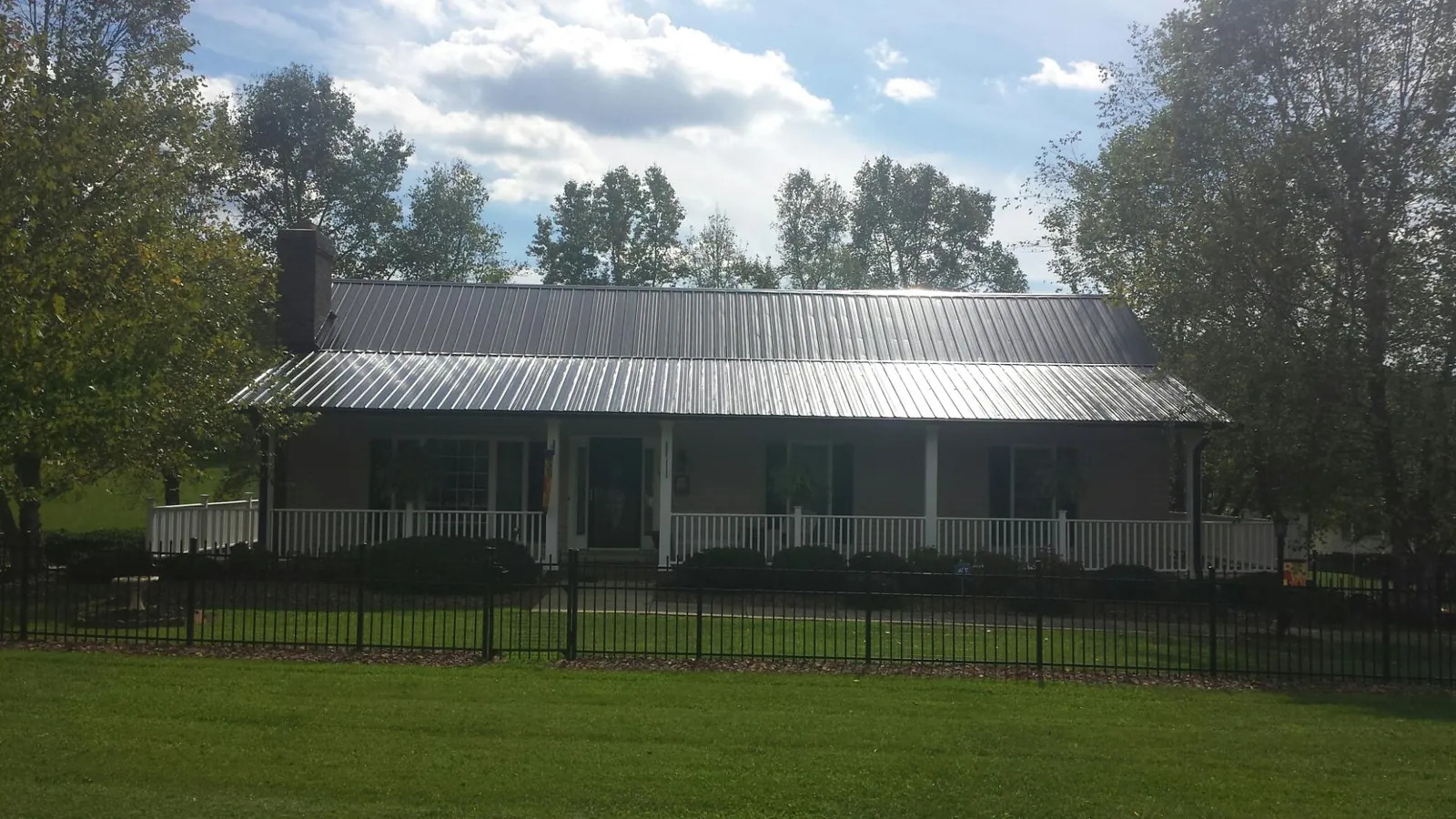 Gray metal roof on a brick ranch with a full width front porch — Gutter Guard Installation work by our crew in Triadelphia
