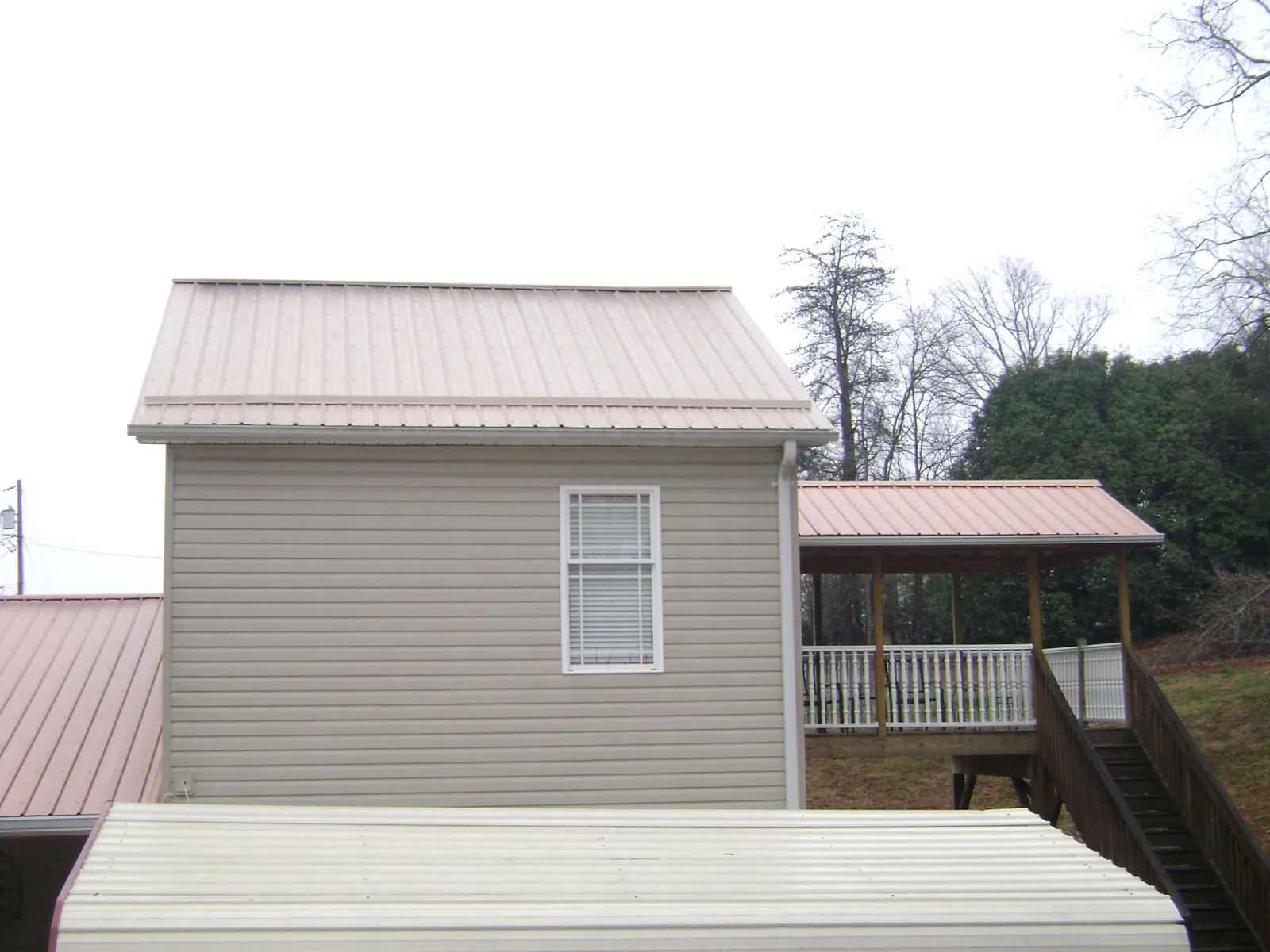 Tan metal roofs on a two story addition and attached porch, from a Roof Replacement job in Triadelphia