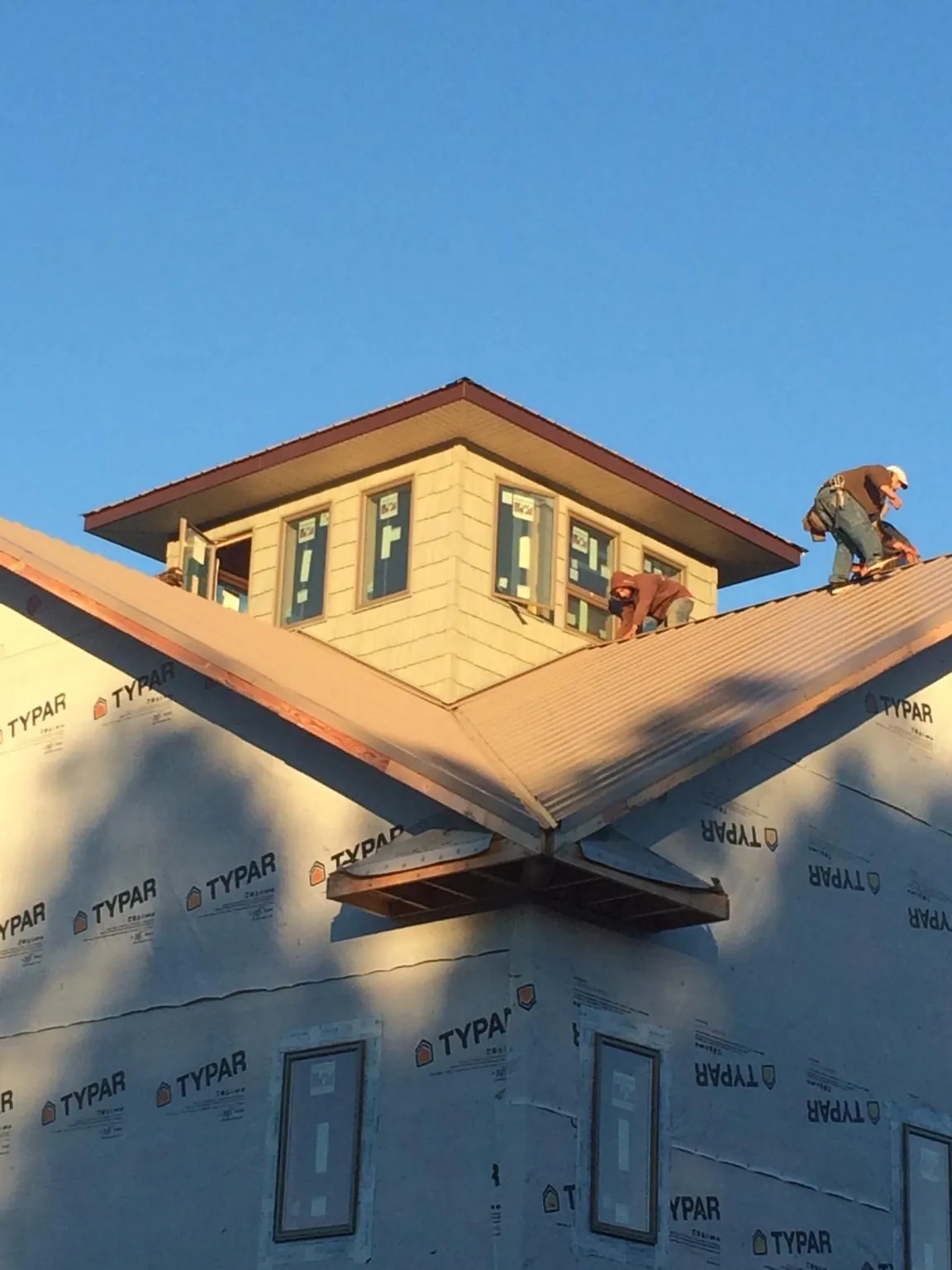 Roofers working around a rooftop cupola on a new metal roof at sunset — Roof Waterproofing in Triadelphia by Roofing Brothers